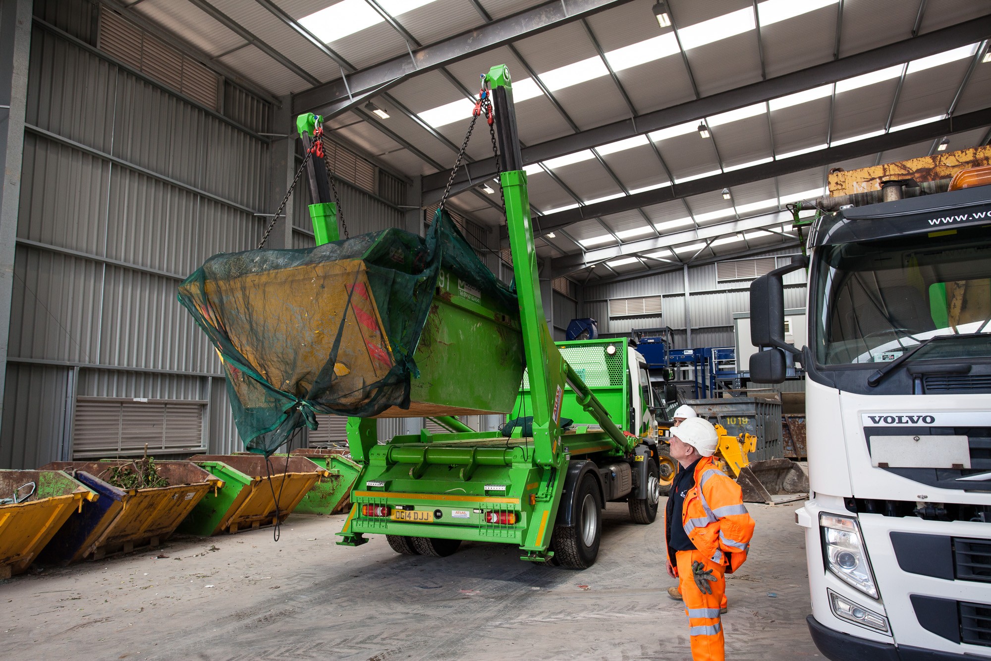 small green skip being unloaded by lorry | Woodford Recycling