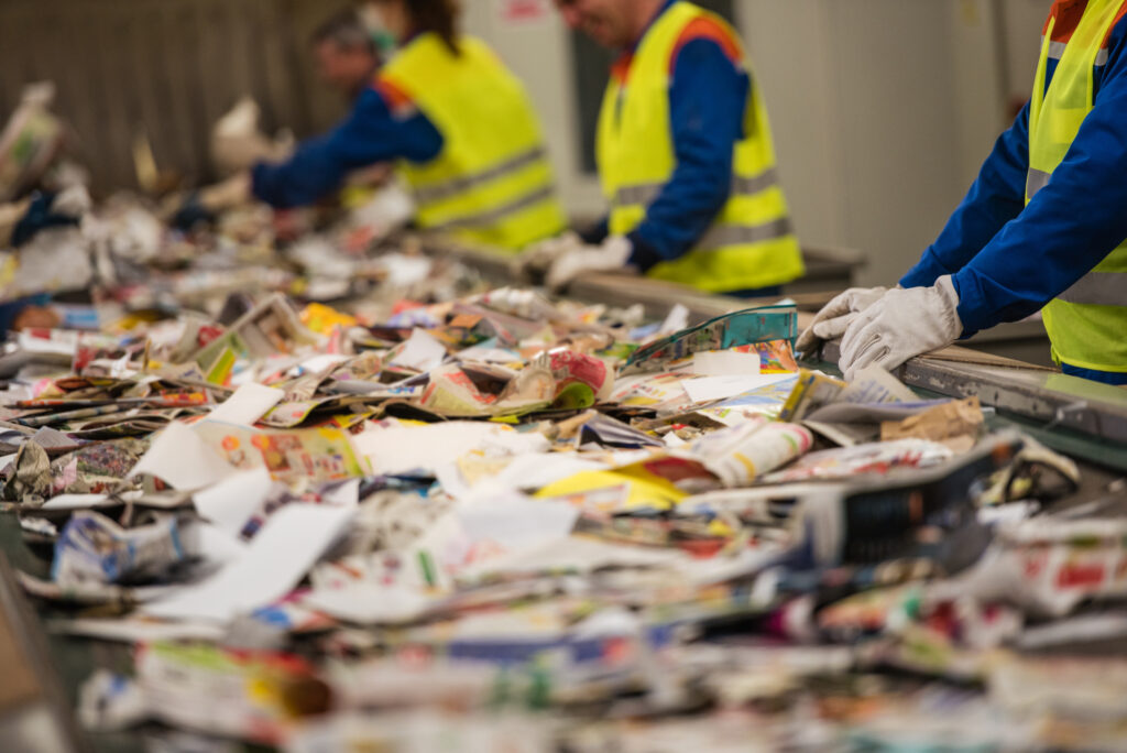 Group of workers sorting papers at recycling plant | Woodford Recycling