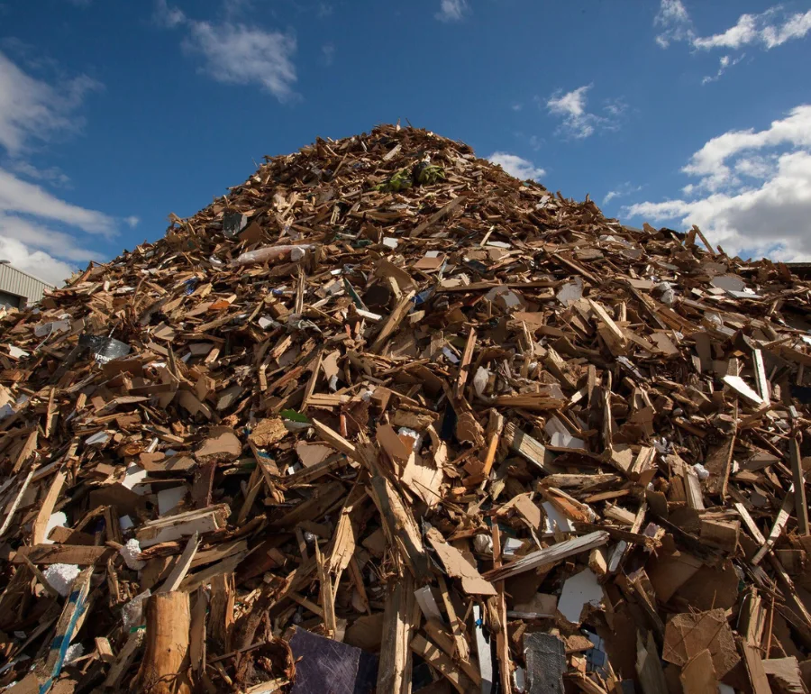 Large pile of timber and wood waste collected for recycling at Woodford Recycling facility.