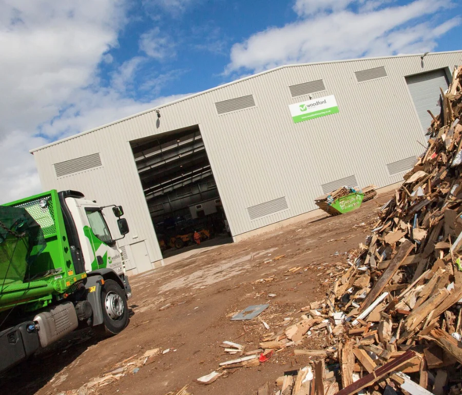 Woodford Recycling facility with green skip hire truck and timber waste ready for recycling.