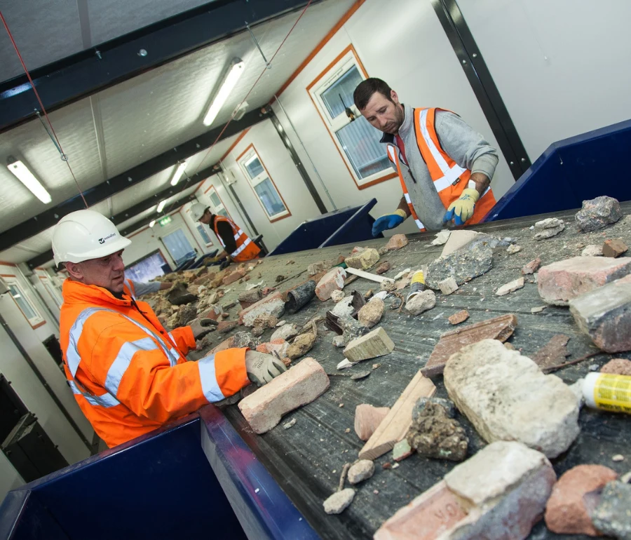Recycling workers sorting mixed construction waste on conveyor belt