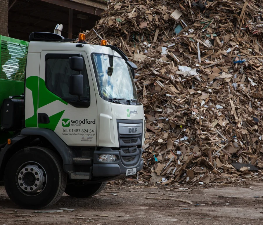 Woodford Recycling truck parked beside large pile of recyclable waste