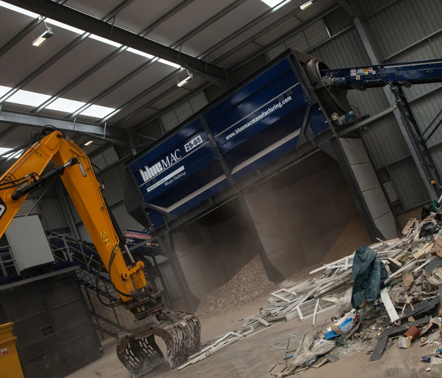 Excavator moving waste materials inside Woodford Recycling processing plant