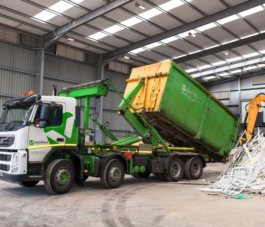 Skip lorry unloading large green container roll on roll off at Woodford