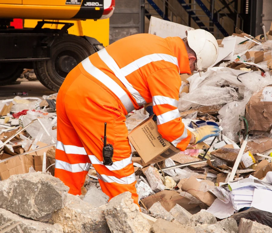 Woodford Recycling worker in high-visibility PPE sorting construction and demolition waste for recycling in the UK