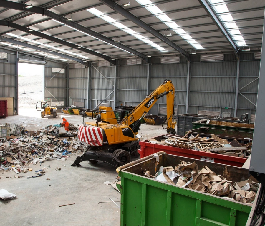 Woodford Recycling skip lorry lifting covered skip container inside UK recycling facility
